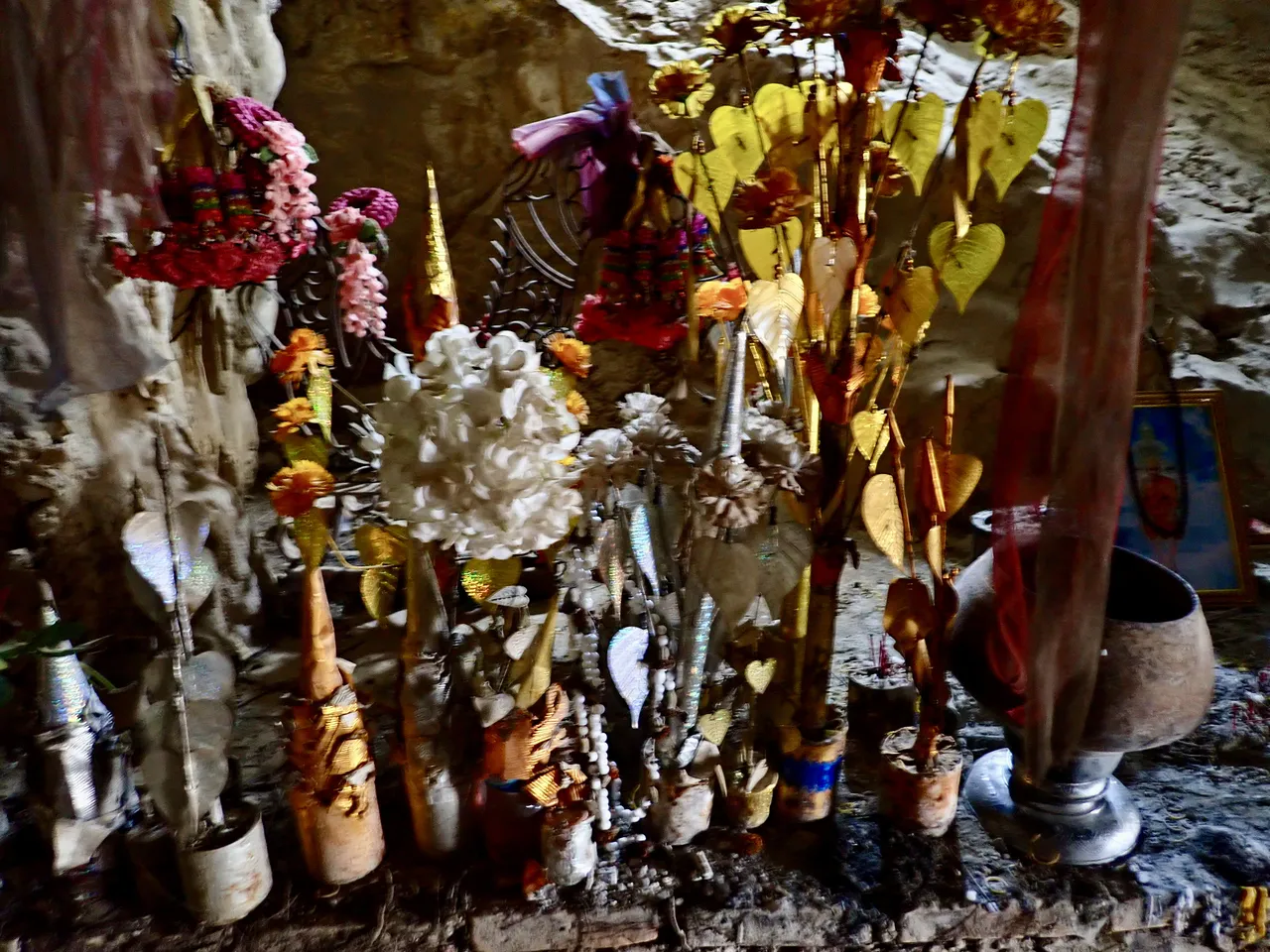 A golden shrine with offerings inside a cave near Vang Vieng