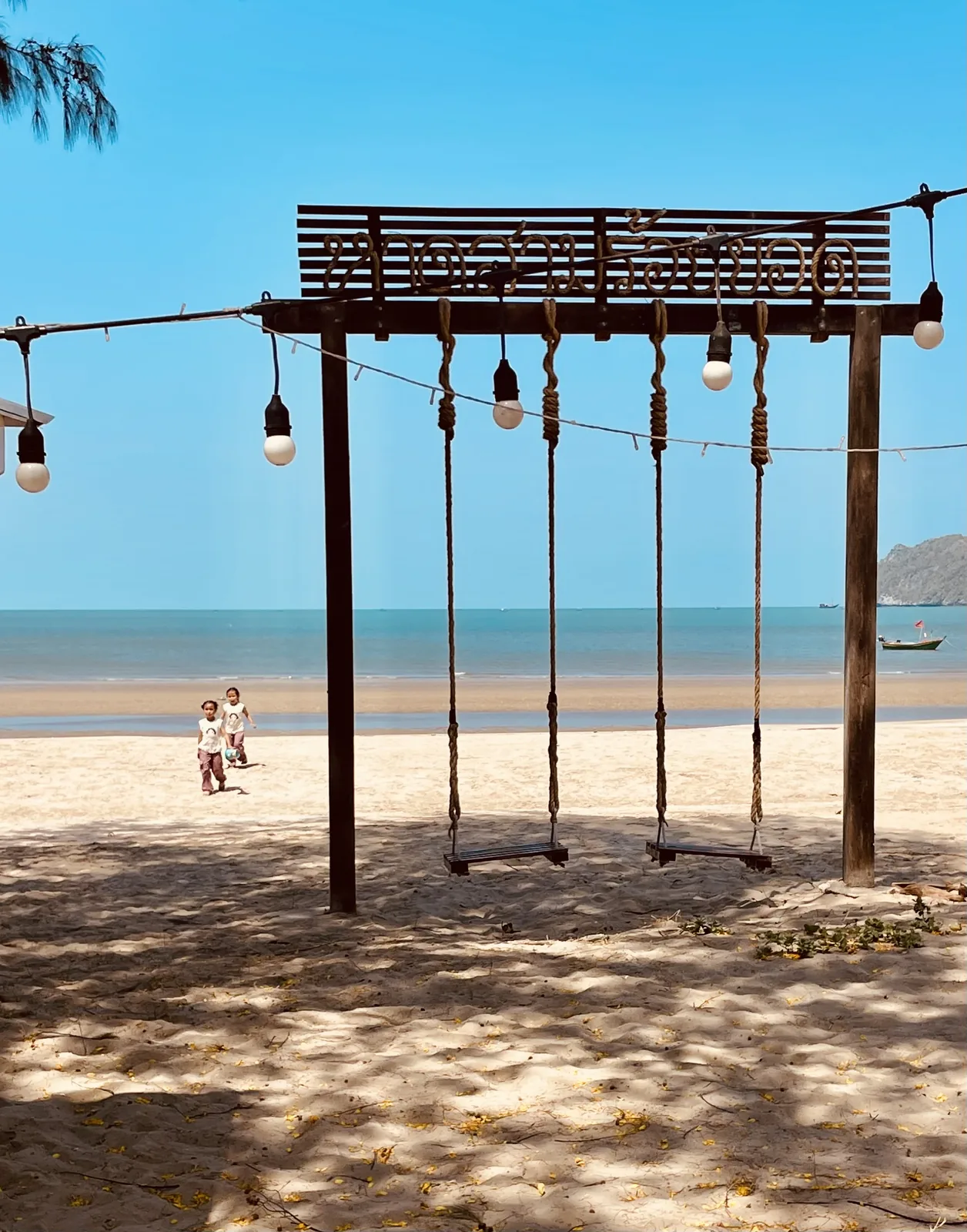 Two girls on the beach near swings at Dolphin Bay Thailand