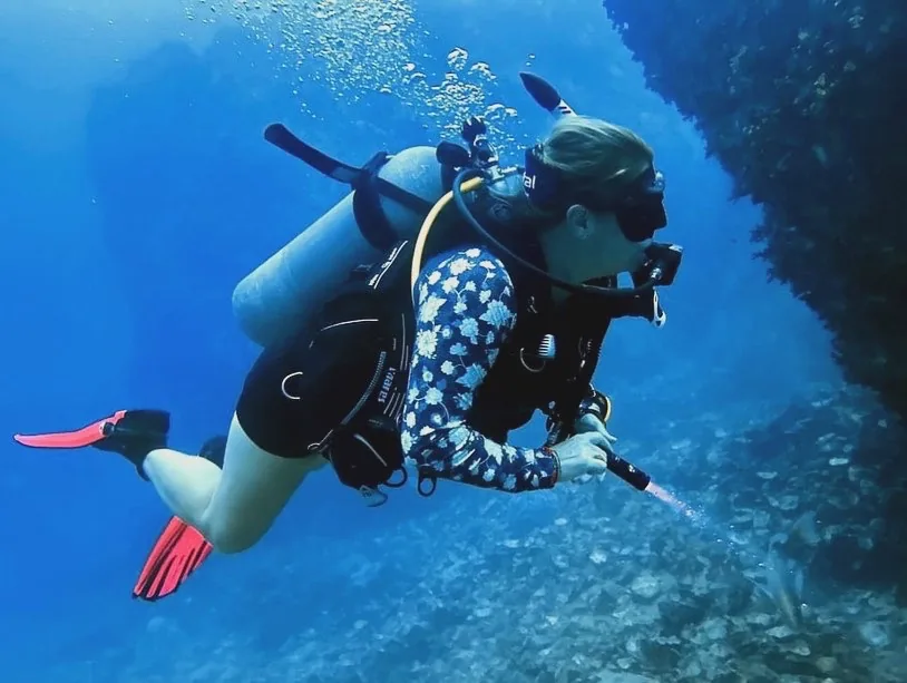 A lady scuba diving with a torch
