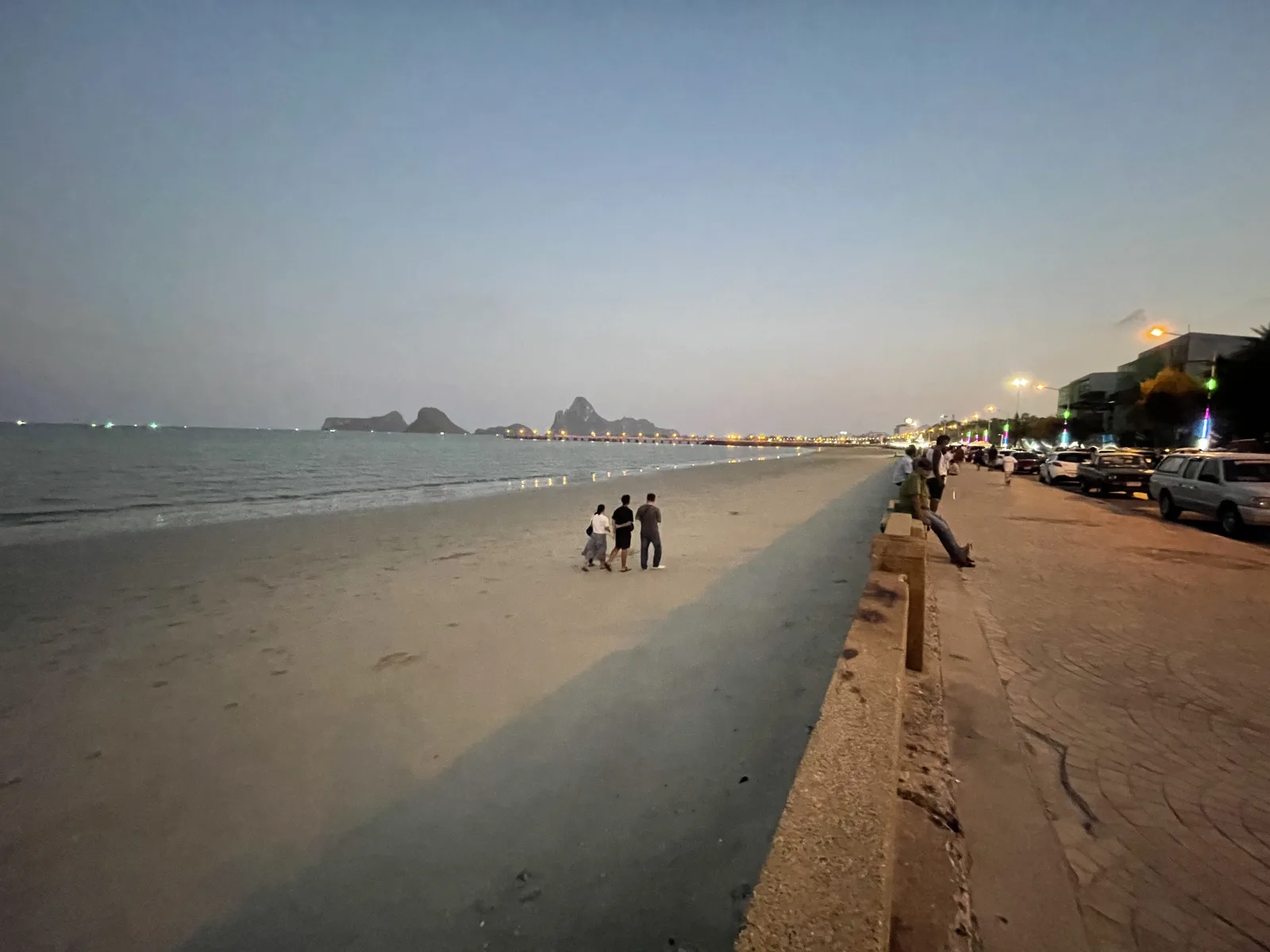 A family walking down the beach of Prachaup Khiri Kan at sunset